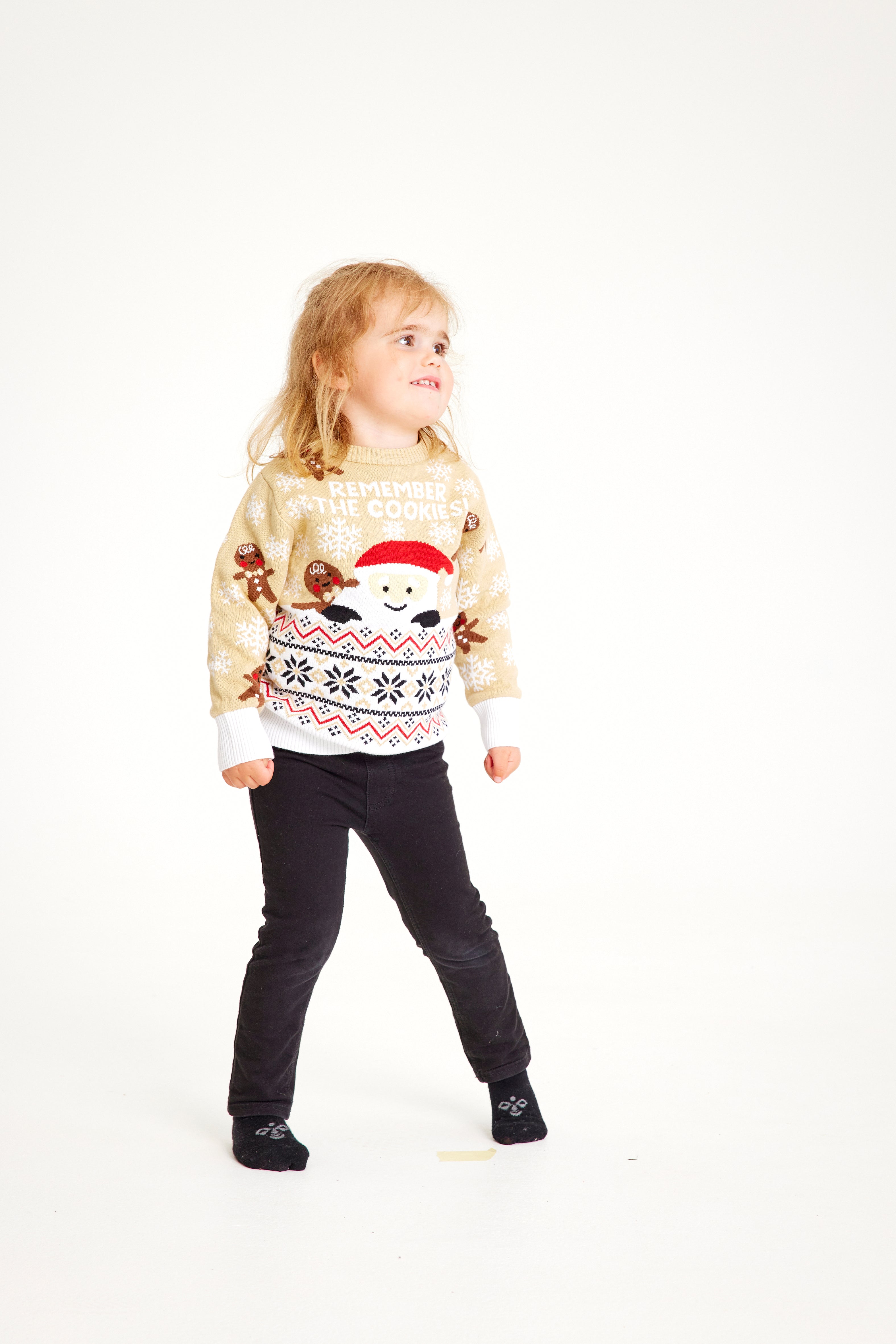 Een kind draagt een beige kersttrui met de quote